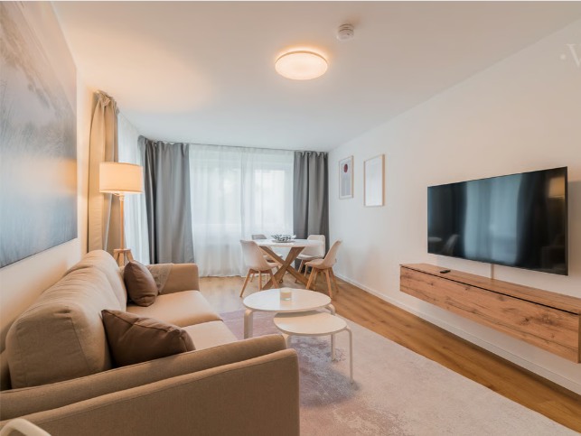 Wohnzimmer in einer Mietwohnung mit Sofa, TV und natürlichem Tageslicht